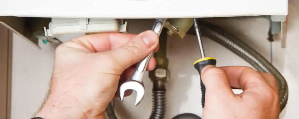Boiler repair technician tightening pipe fittings and connections in Modesto, CA