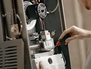 Furnace repair technician inspecting internal components and wiring in Modesto, CA