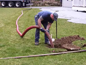 Septic pumping technician servicing a residential septic tank with a vacuum hose in Modesto, CA
