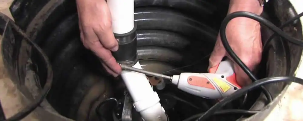 Sump pump installation technician connecting PVC discharge piping in Modesto, CA